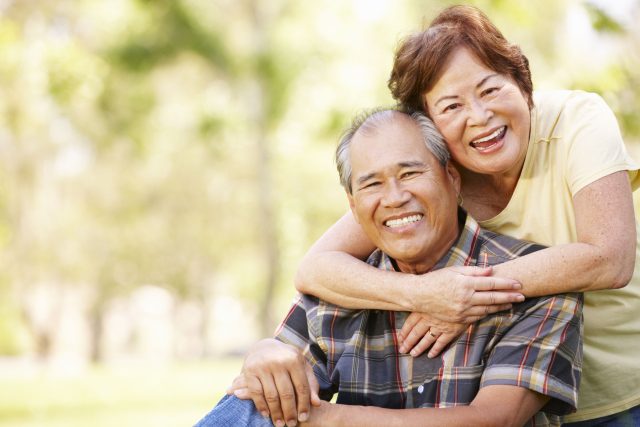 a man and woman hugging each other in a park.