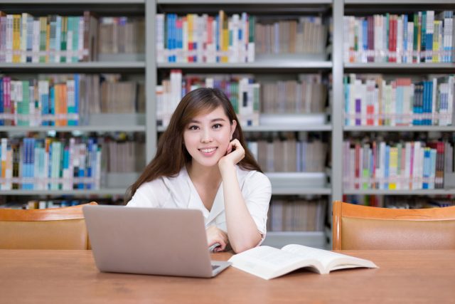 a woman sitting at a table in front of a laptop computer.