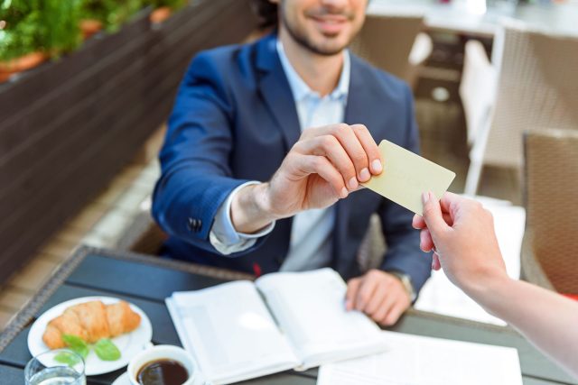 a man handing a business card to a woman.